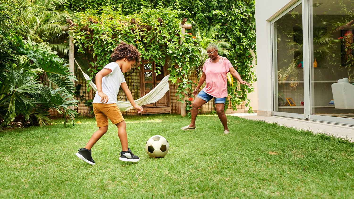 Grandson and grandma playing with the ball in the yard
