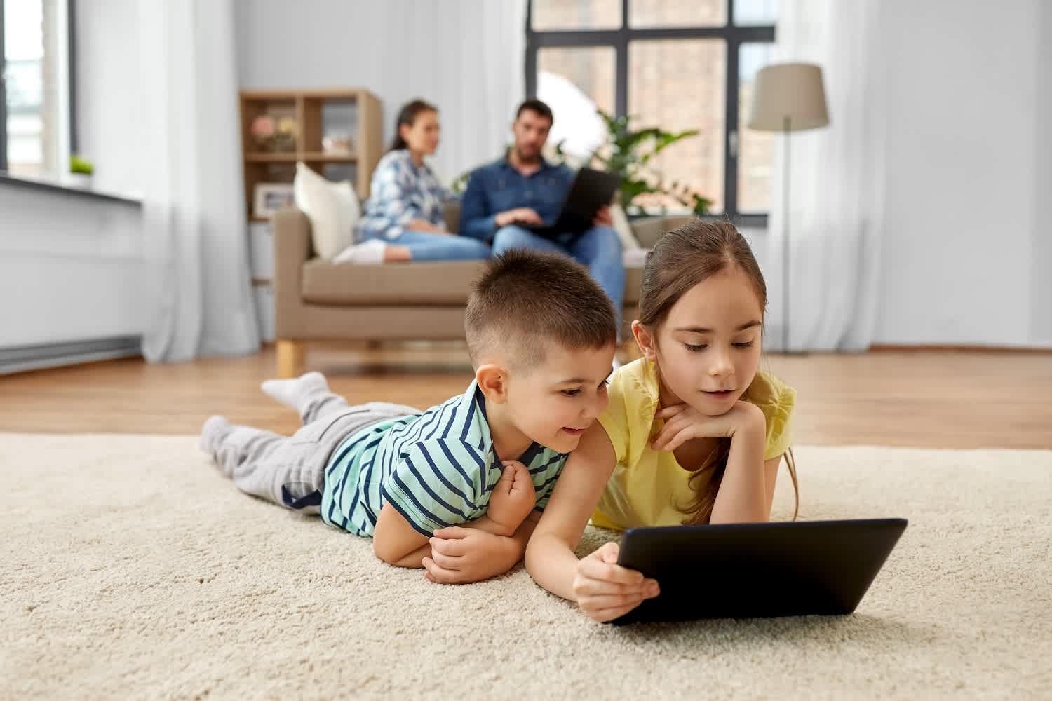 Kids using tablet together on living room floor