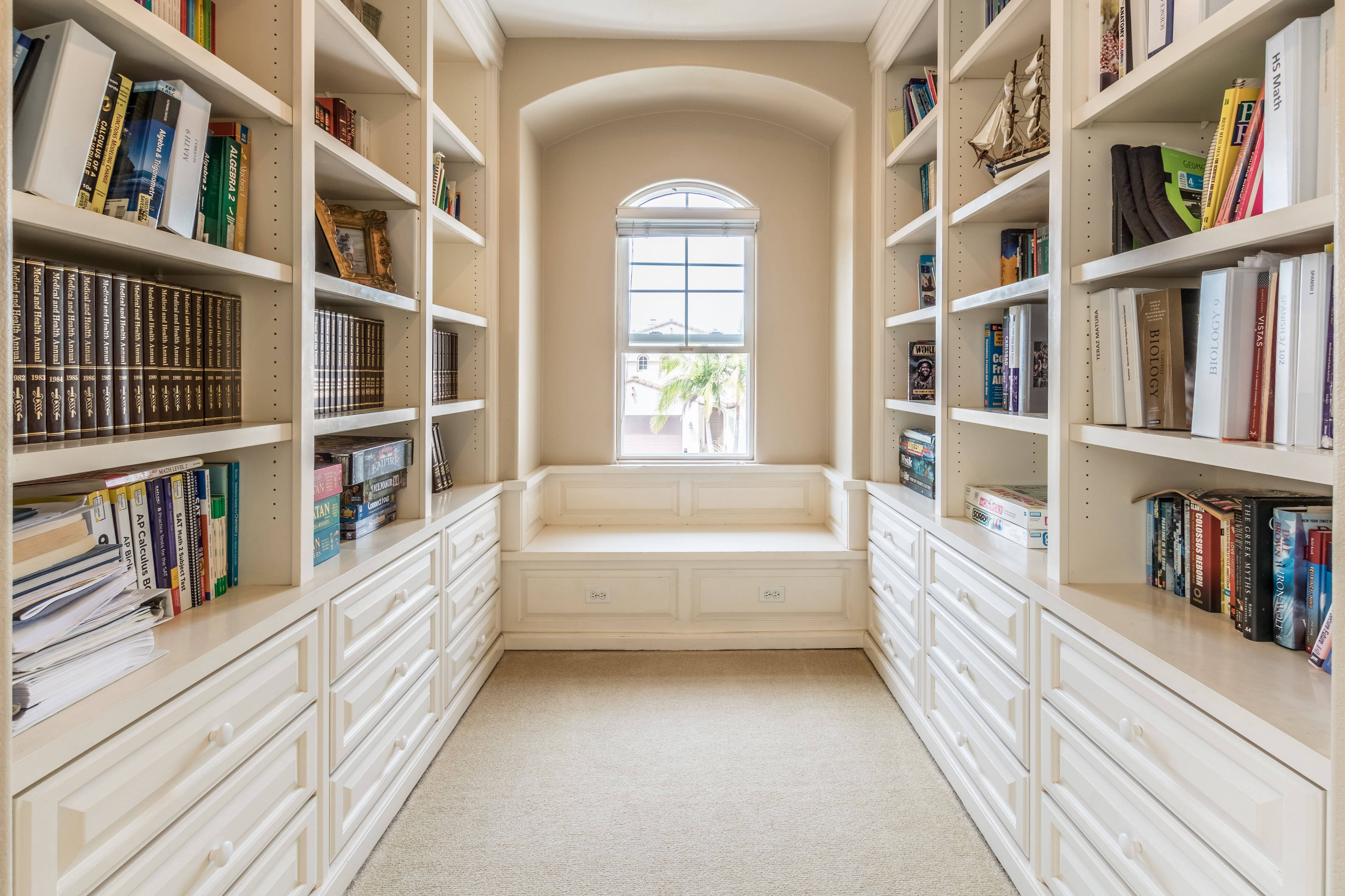 Walk-in-closet library with white shelves and bench seat