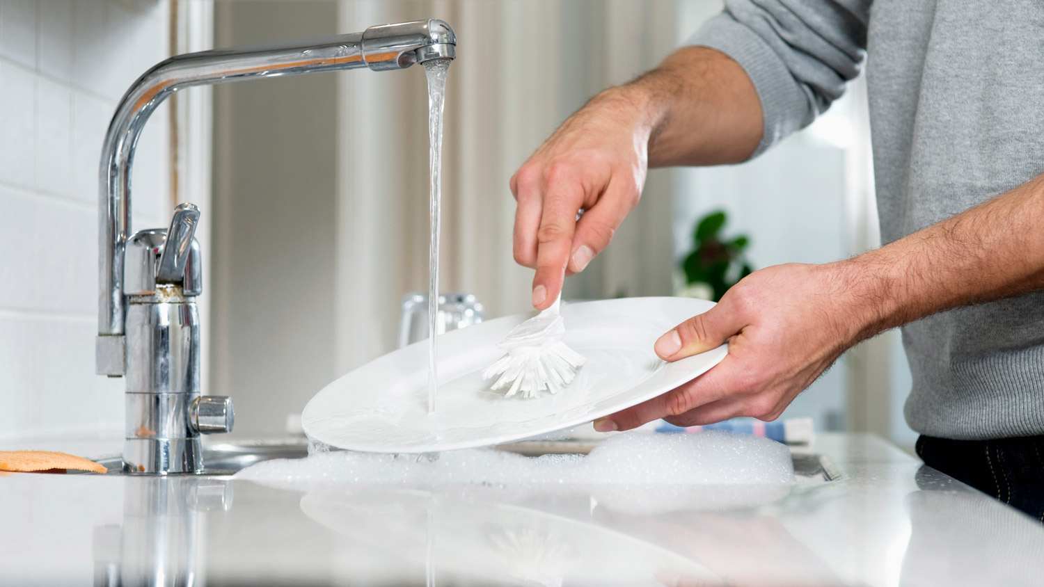 Detail of a man’s hands doing the dishes