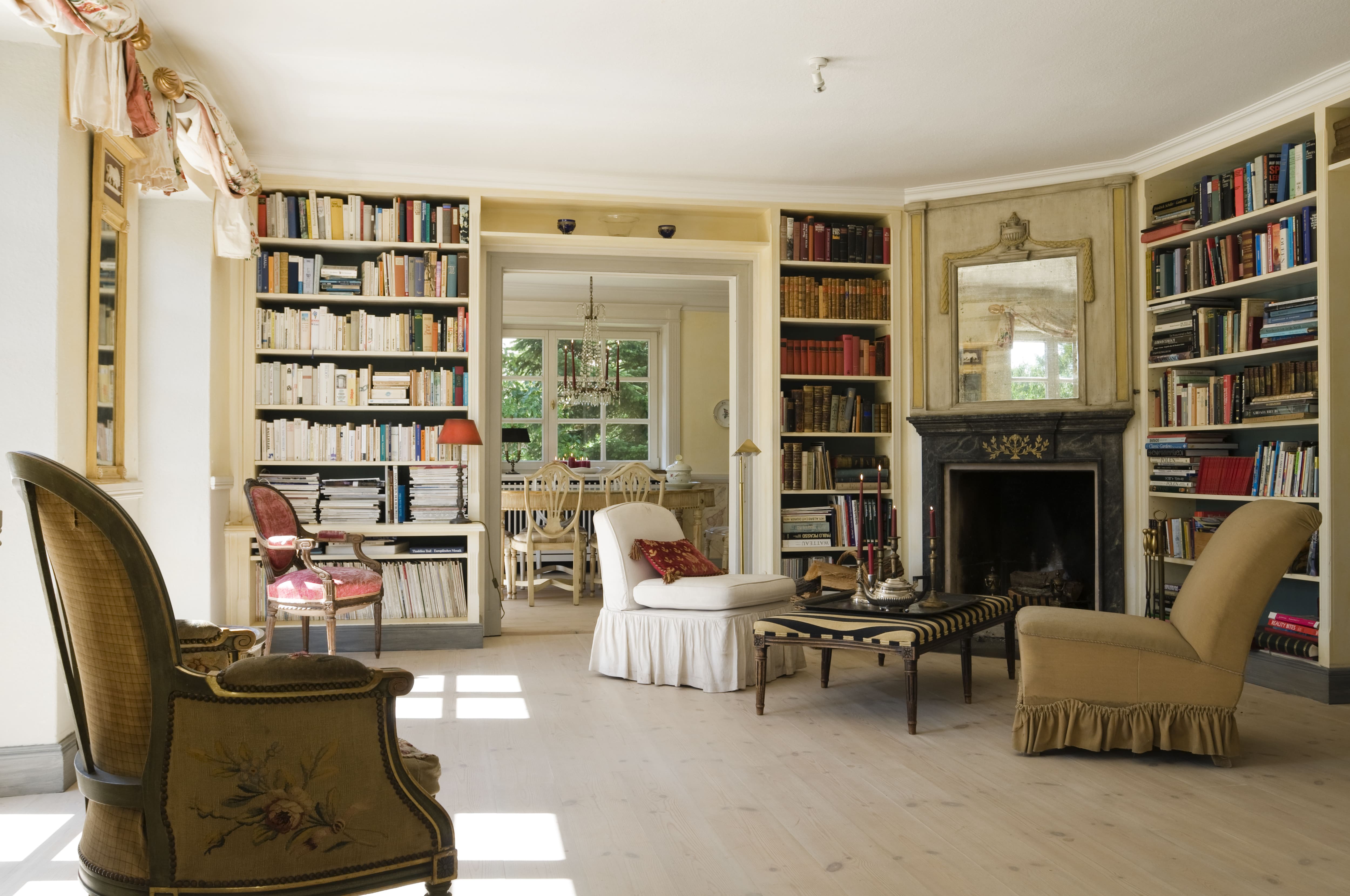 Library in a restored 1820s German farmhouse complete with built-in bookshelves, vintage furniture, and a fireplace
