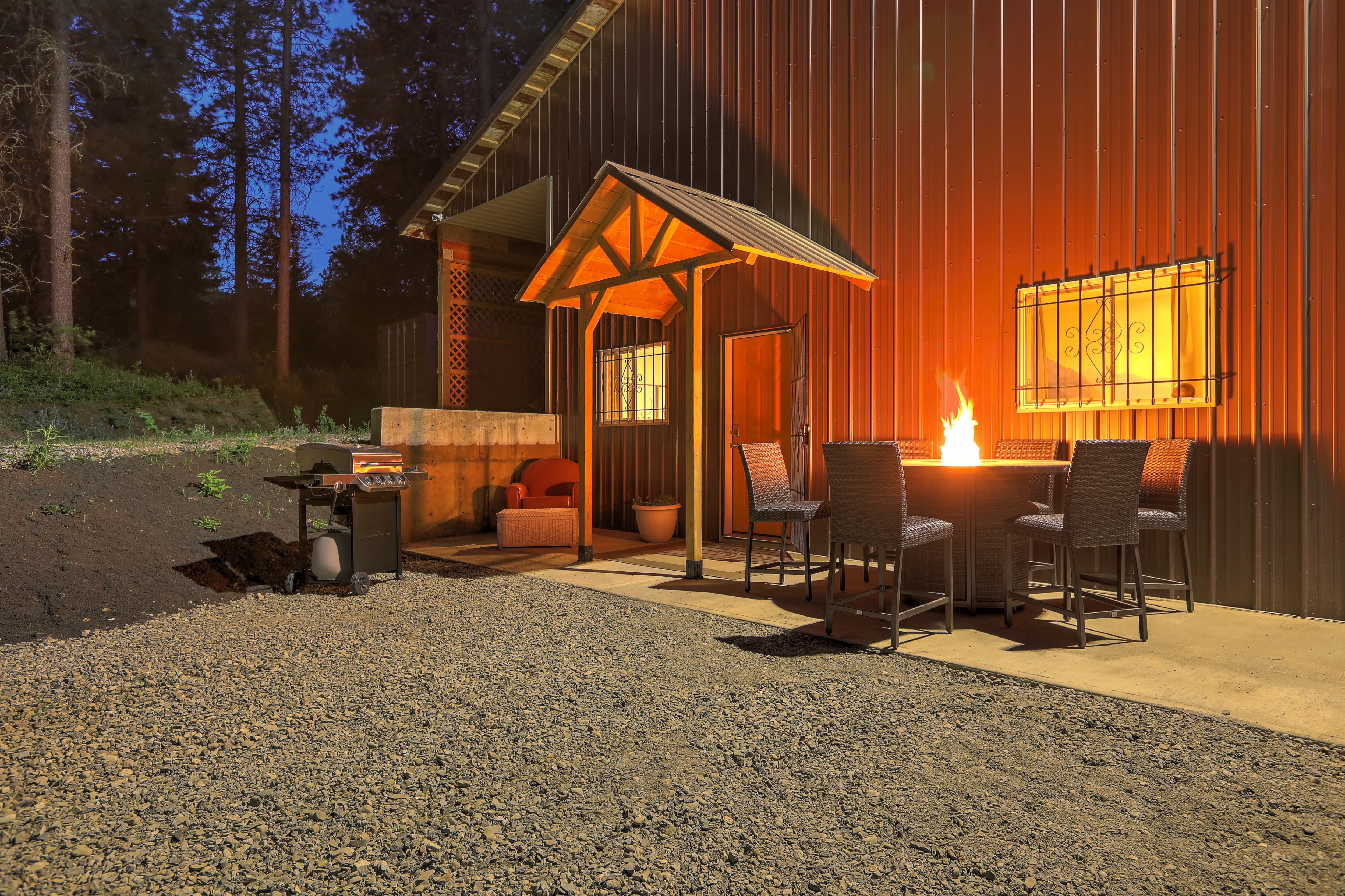 A large metal barndominium with a patio set and propane fireplace outside the front door