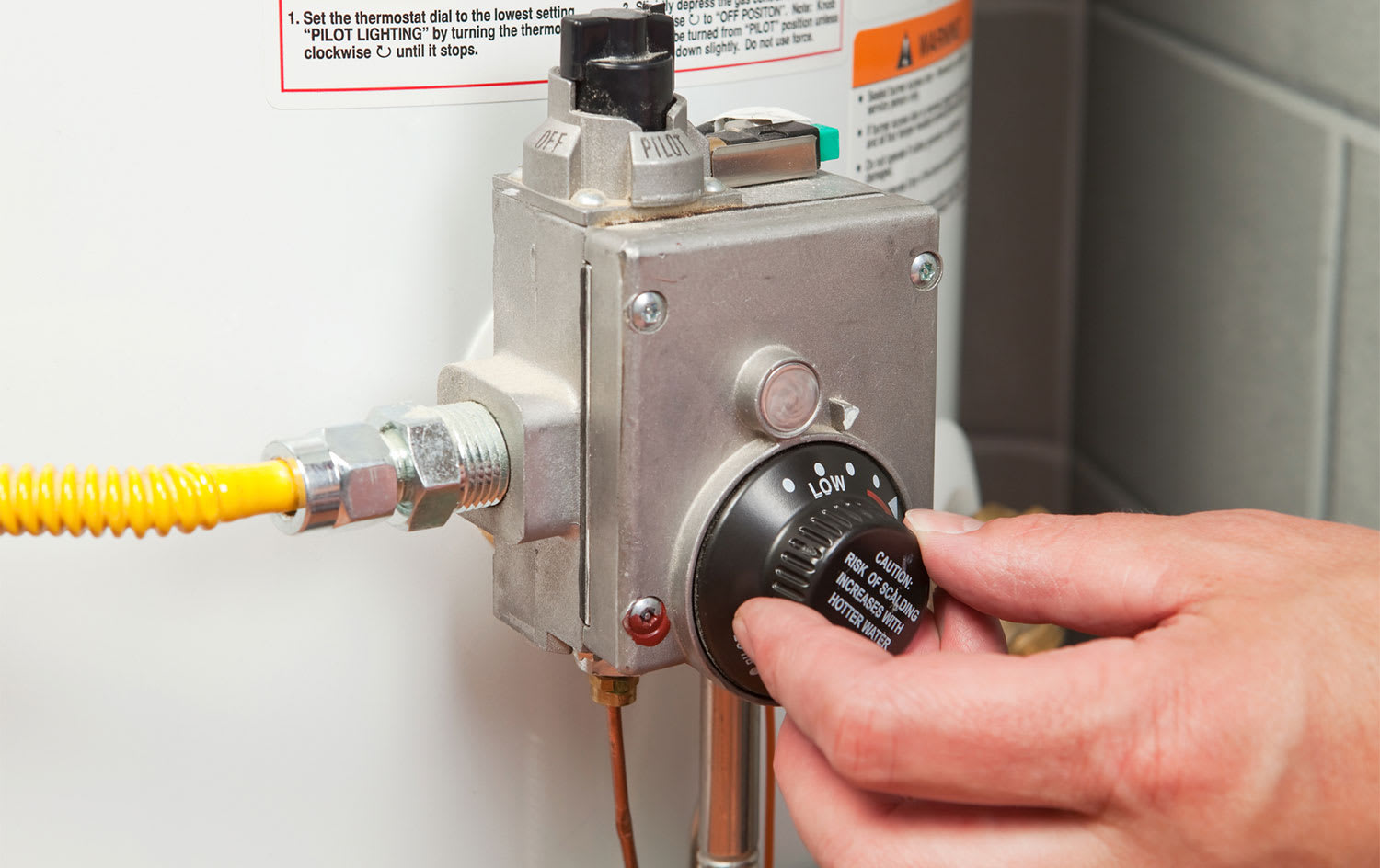 Hand adjusting water heater thermostat