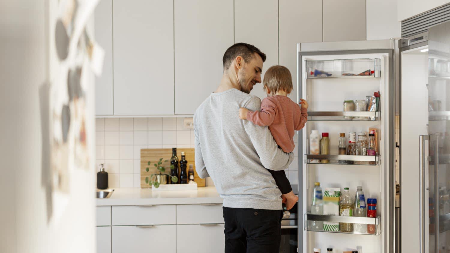 Father carrying toddler daughter in kitchen