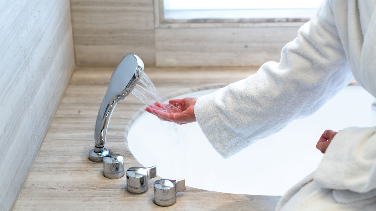 Woman checking temperature touching running water