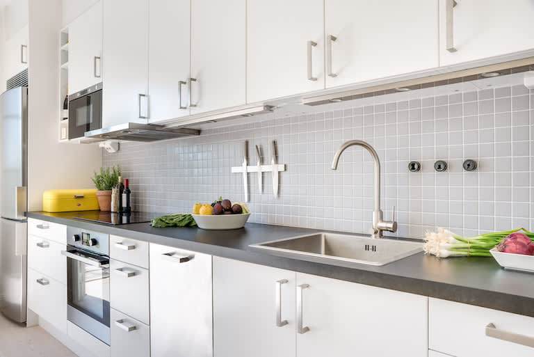 interior view of kitchen with gray countertop and white flat cabinet doors with silver handles
