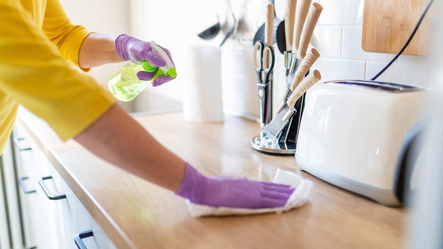 Hands in gloves disinfecting a kitchen counter