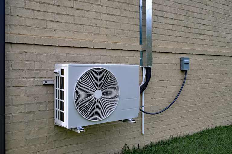 a white ductless mini-split a/c is attached to brick wall