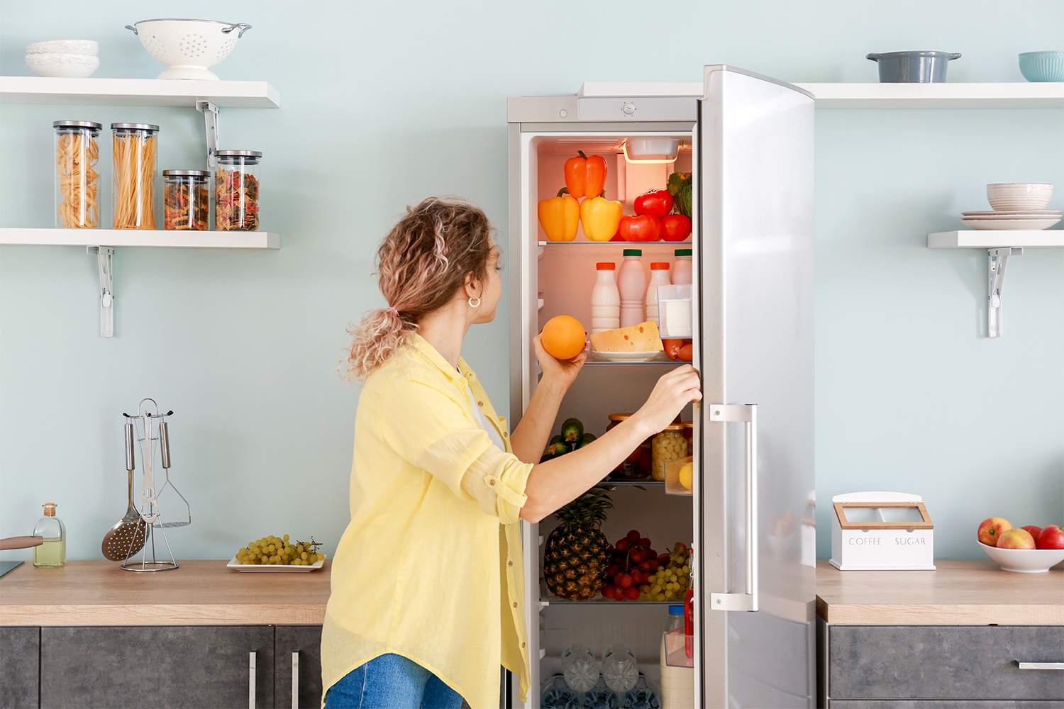 A woman opening fridge to find ingredients