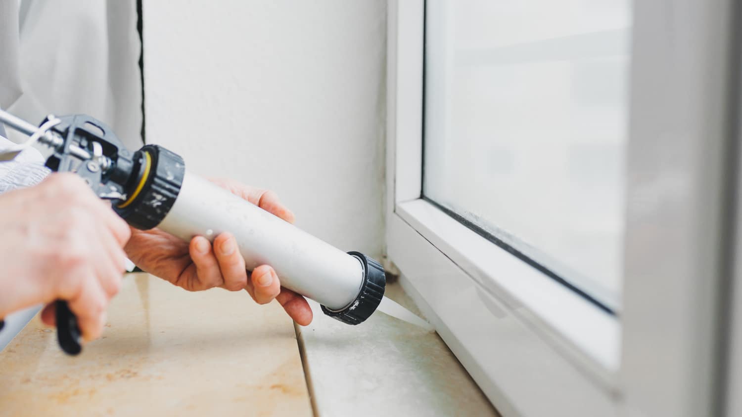 Close-up of a hand winterizing a window