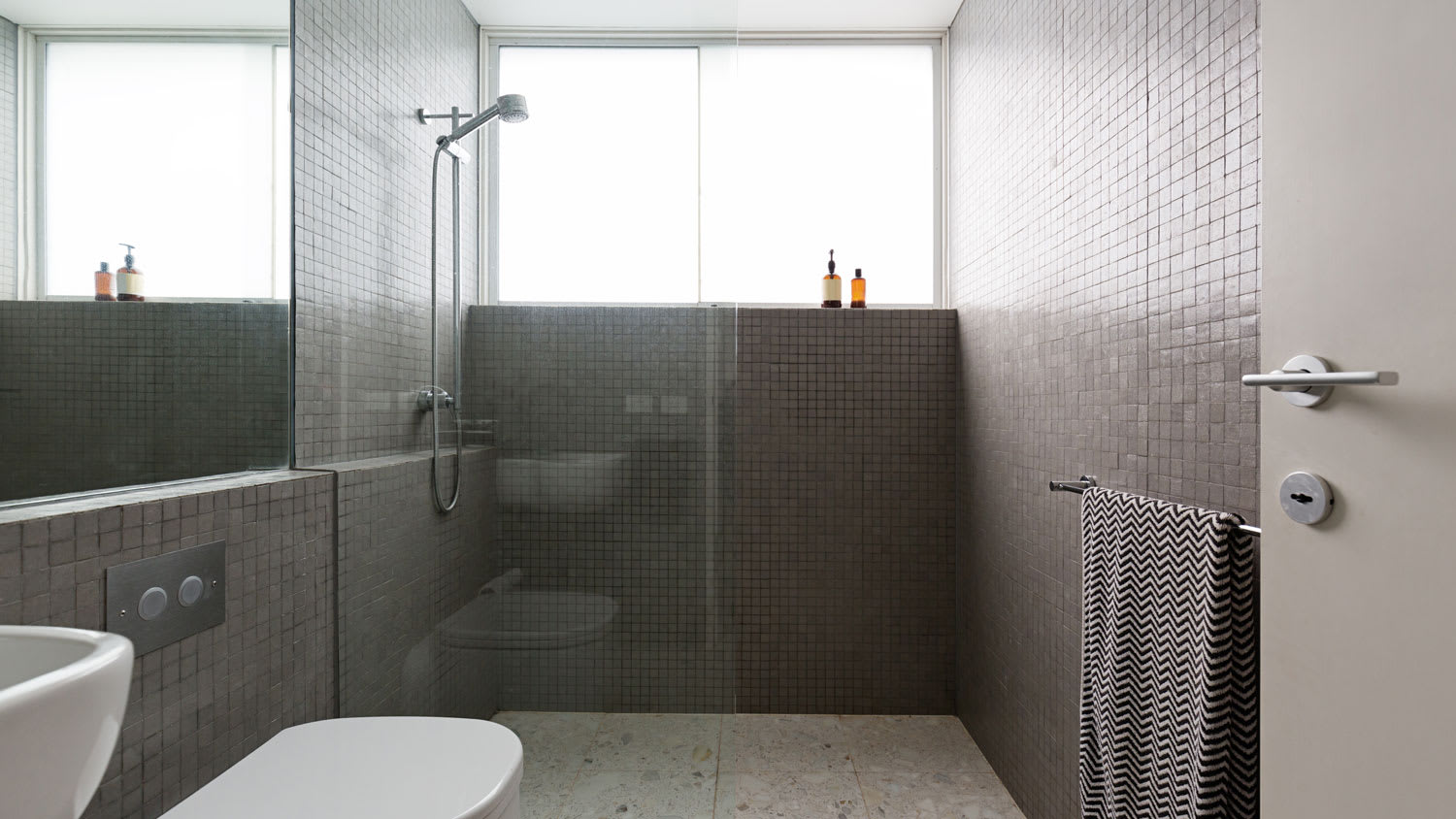 A walk-in shower with black tiles