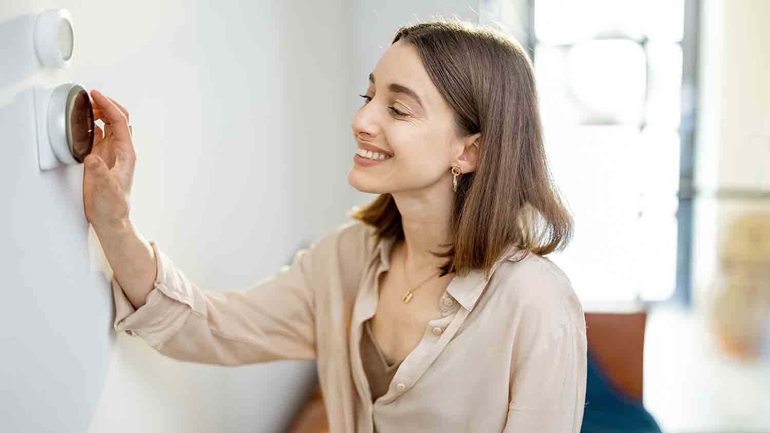 woman checking setting on thermostat