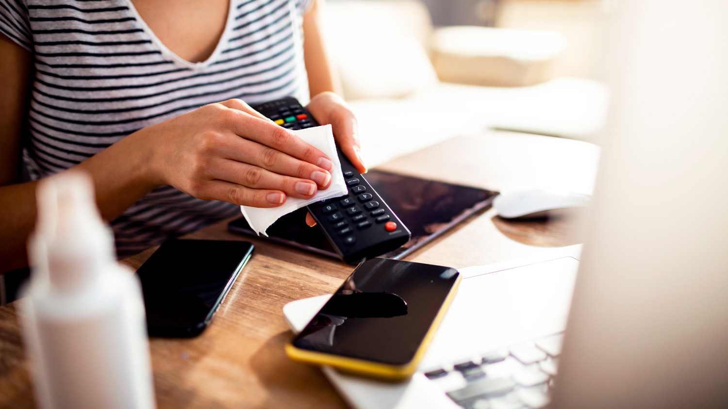 A woman’s hands disinfecting tv remote