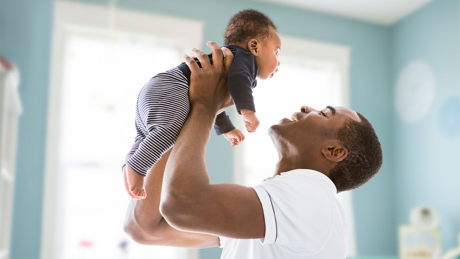 Father in nursery room holding his baby son
