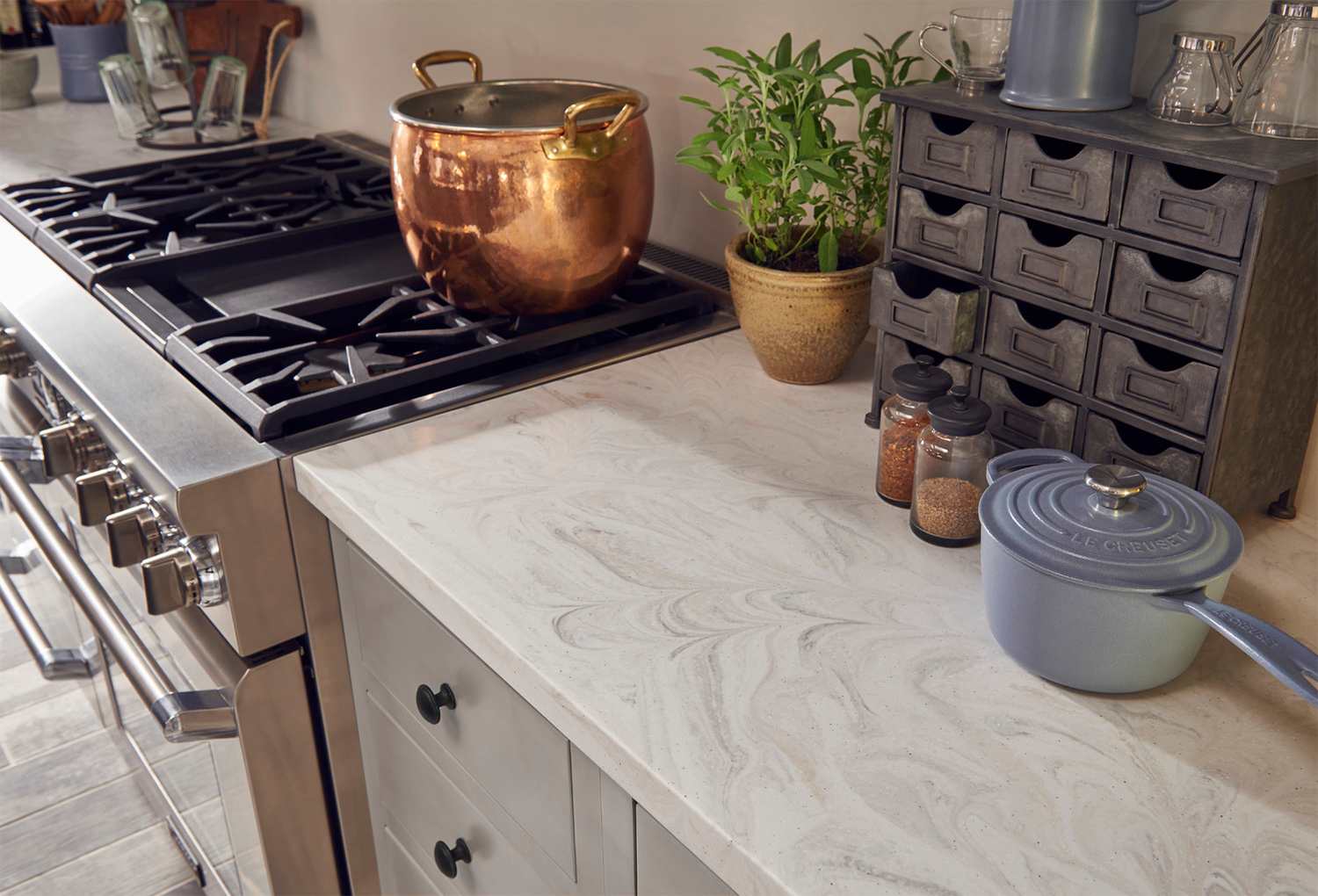 Light Corian kitchen counter around stove with copper pot