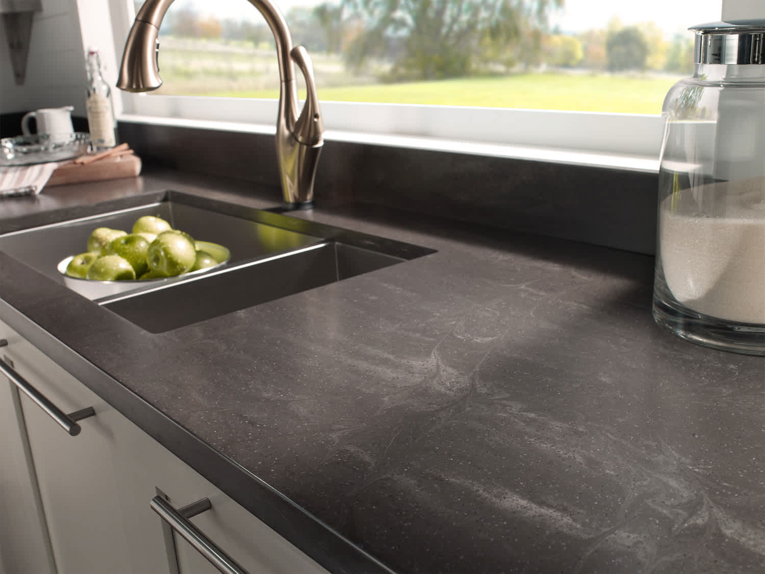 Dark Corian kitchen counter around sink and washed apples