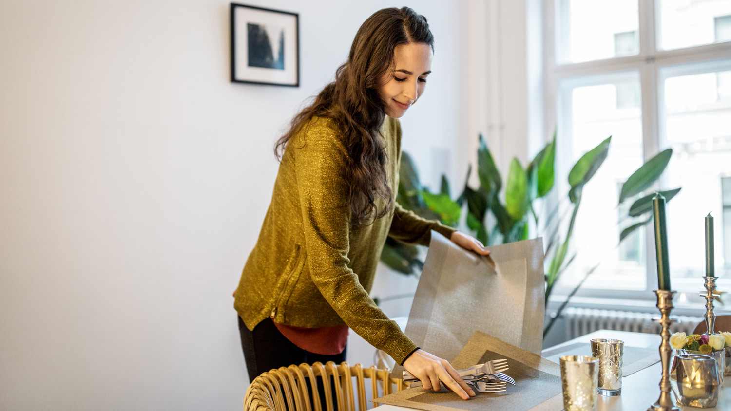 A woman setting the table by placing placemats