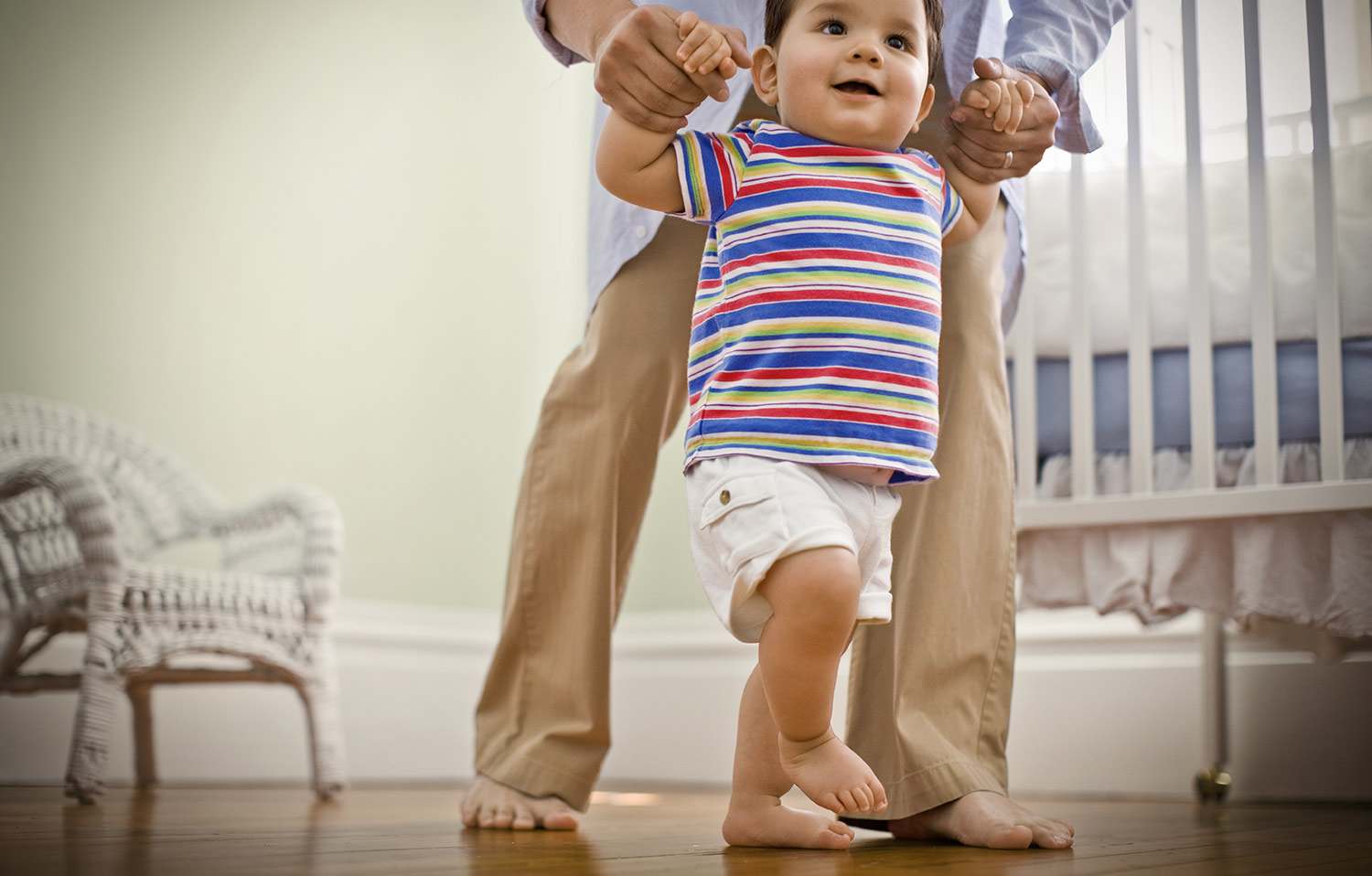Toddler being helped across hardwood floor
