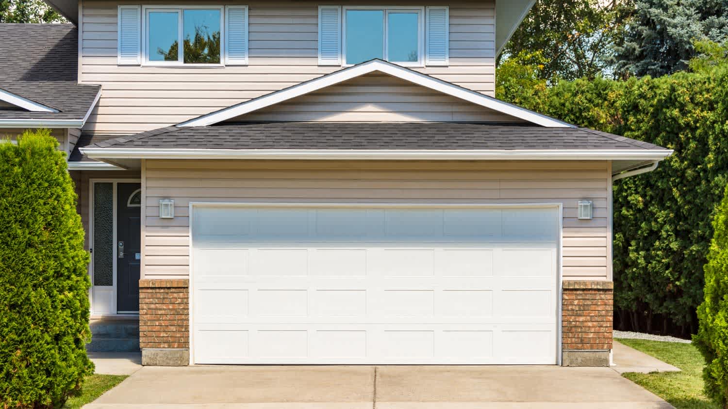 A wide garage door with a concrete driveway leading to it