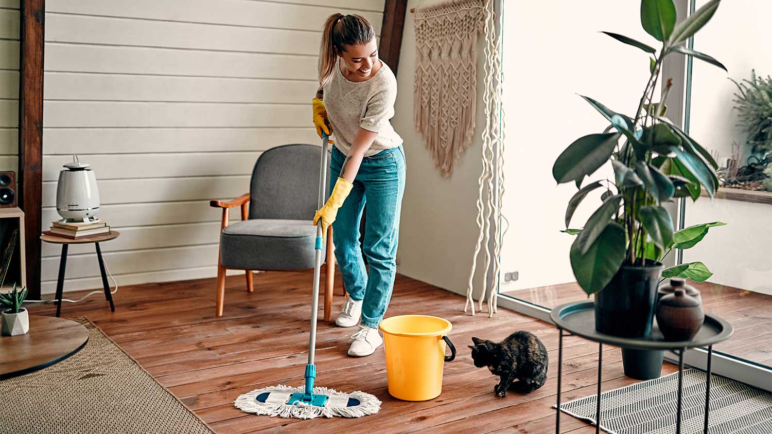 woman smiling to her cat is mopping the floor