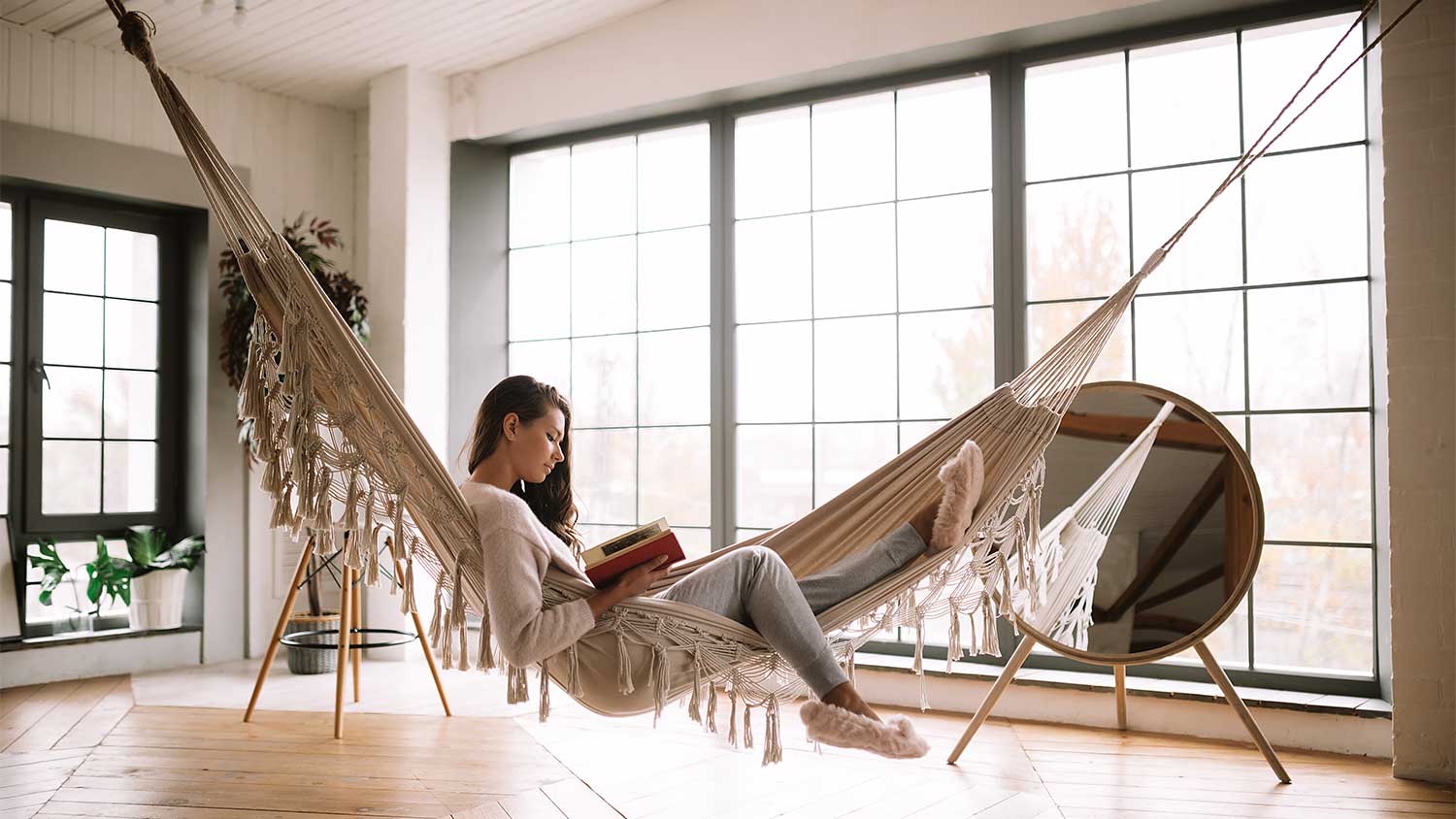 Woman lying in a hammock reading a book