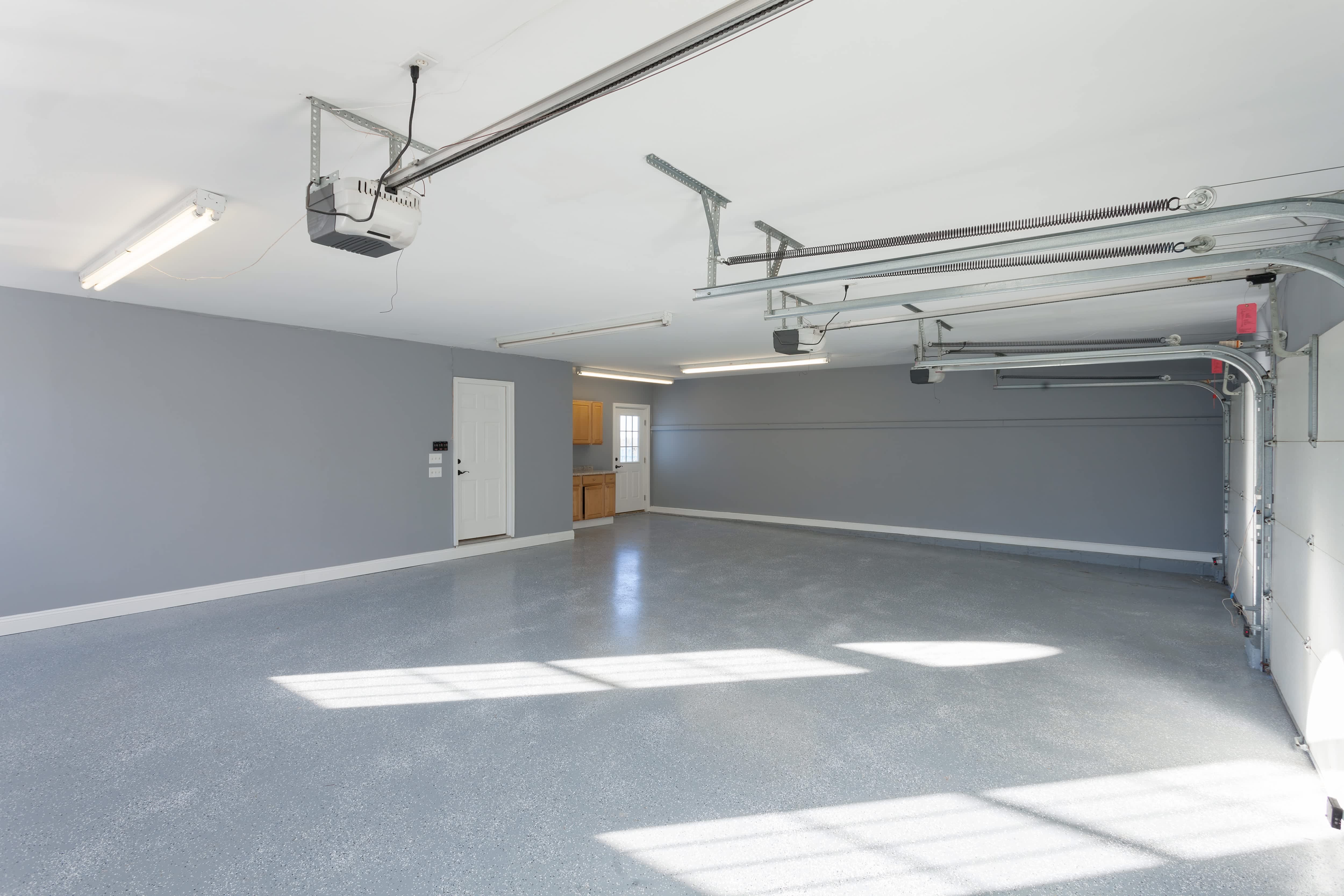 An empty home garage with gray walls and overhead wraparound lights