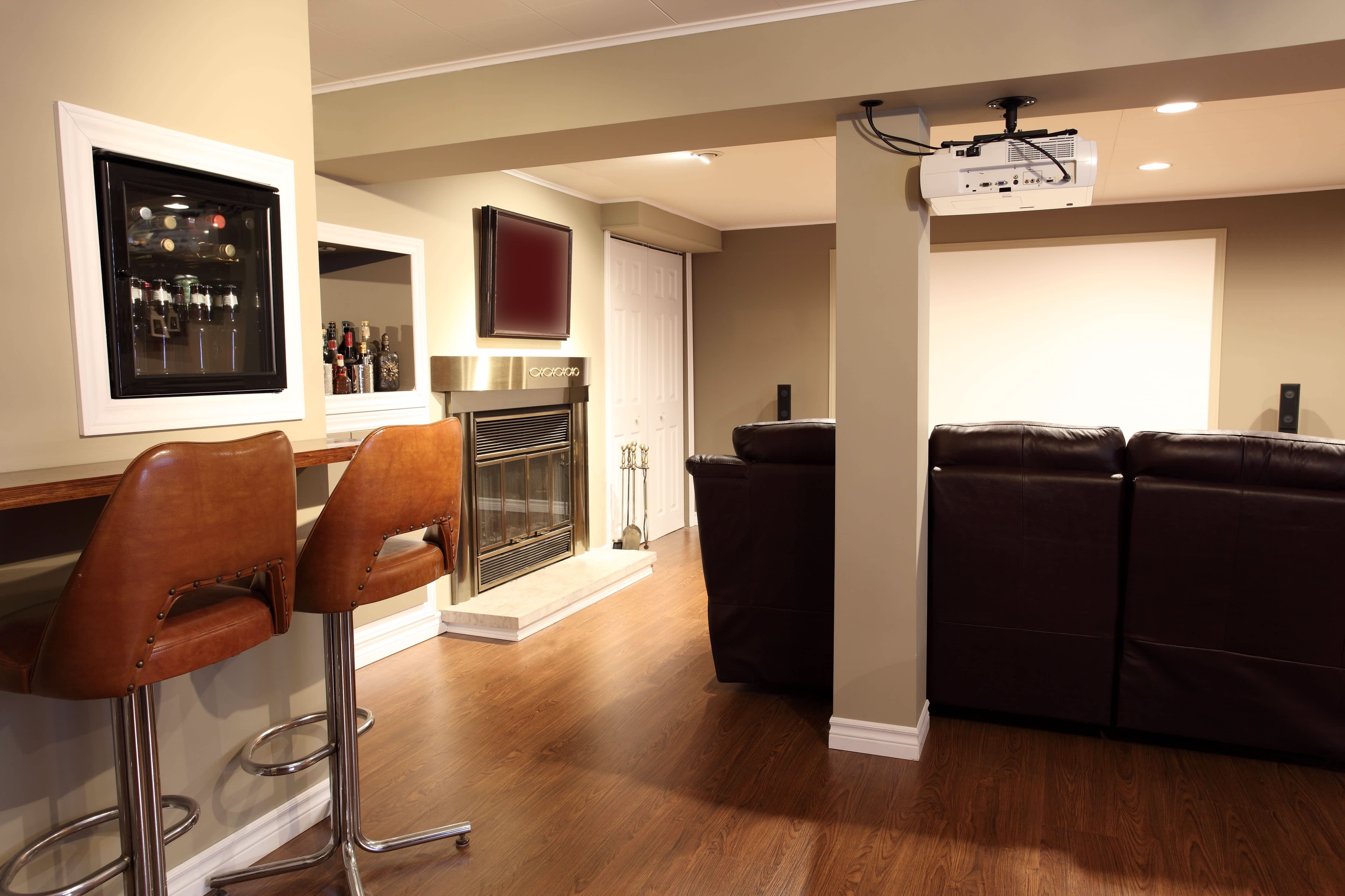 Basement rec room with mini fridge unit in wall and a projector screen