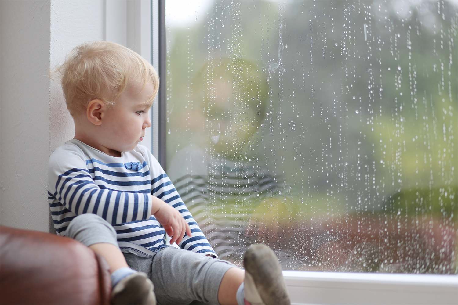 A baby watching rain out the window