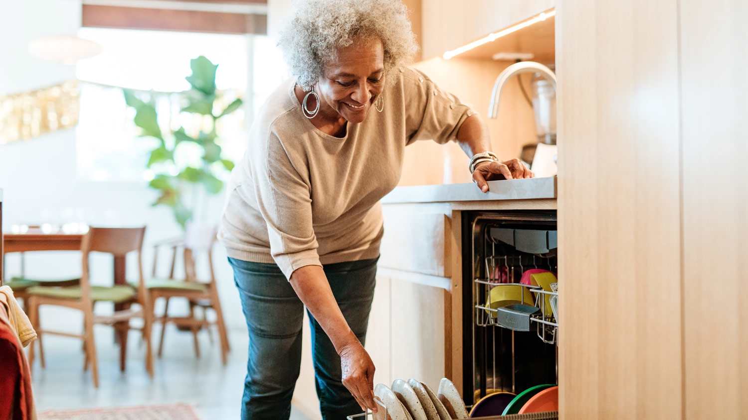 A senior woman loading the dishwasher with dishes