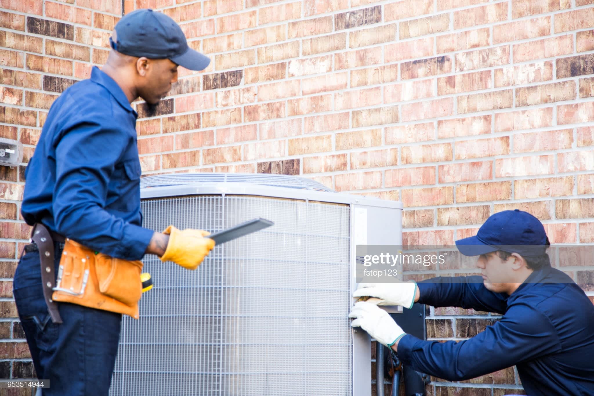 Two technicians repairing a HVAC system