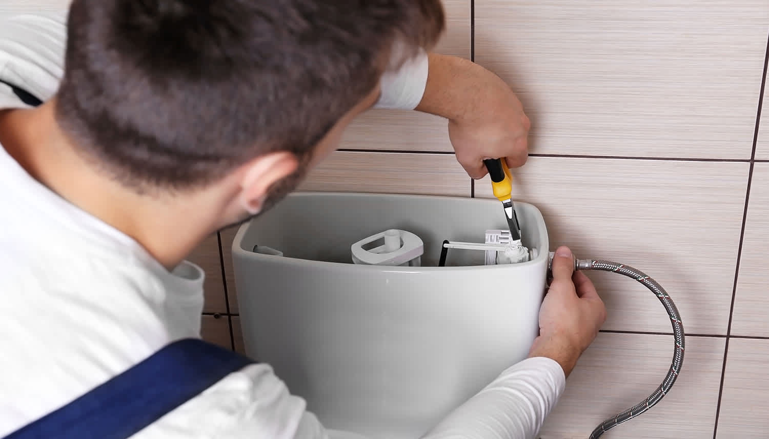 Plumber repairs toilet