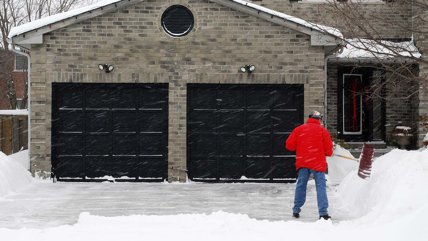 Man shoveling snow outside garage