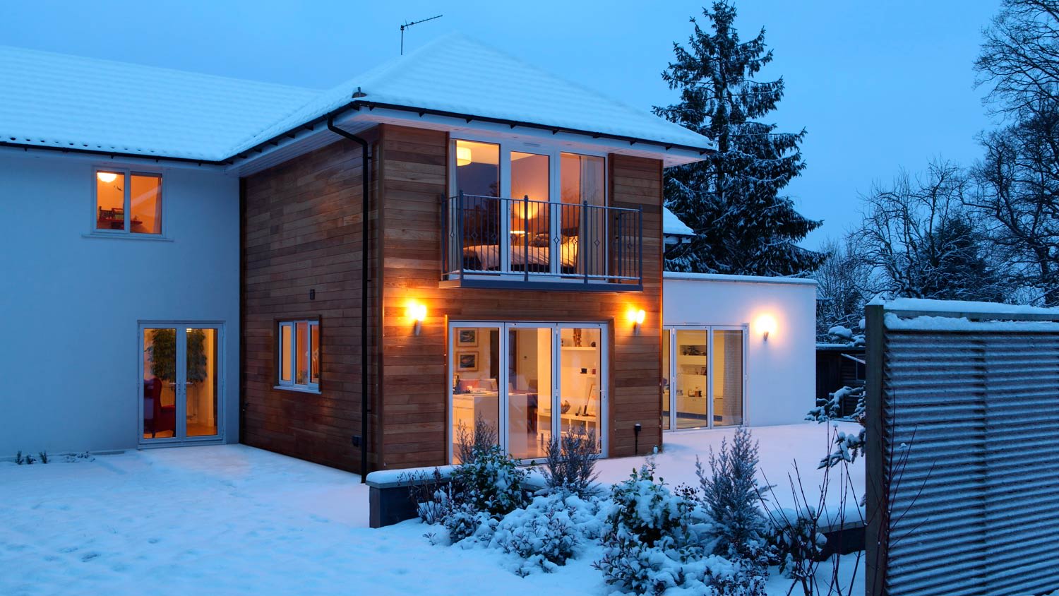 An illuminated house at dusk in snow
