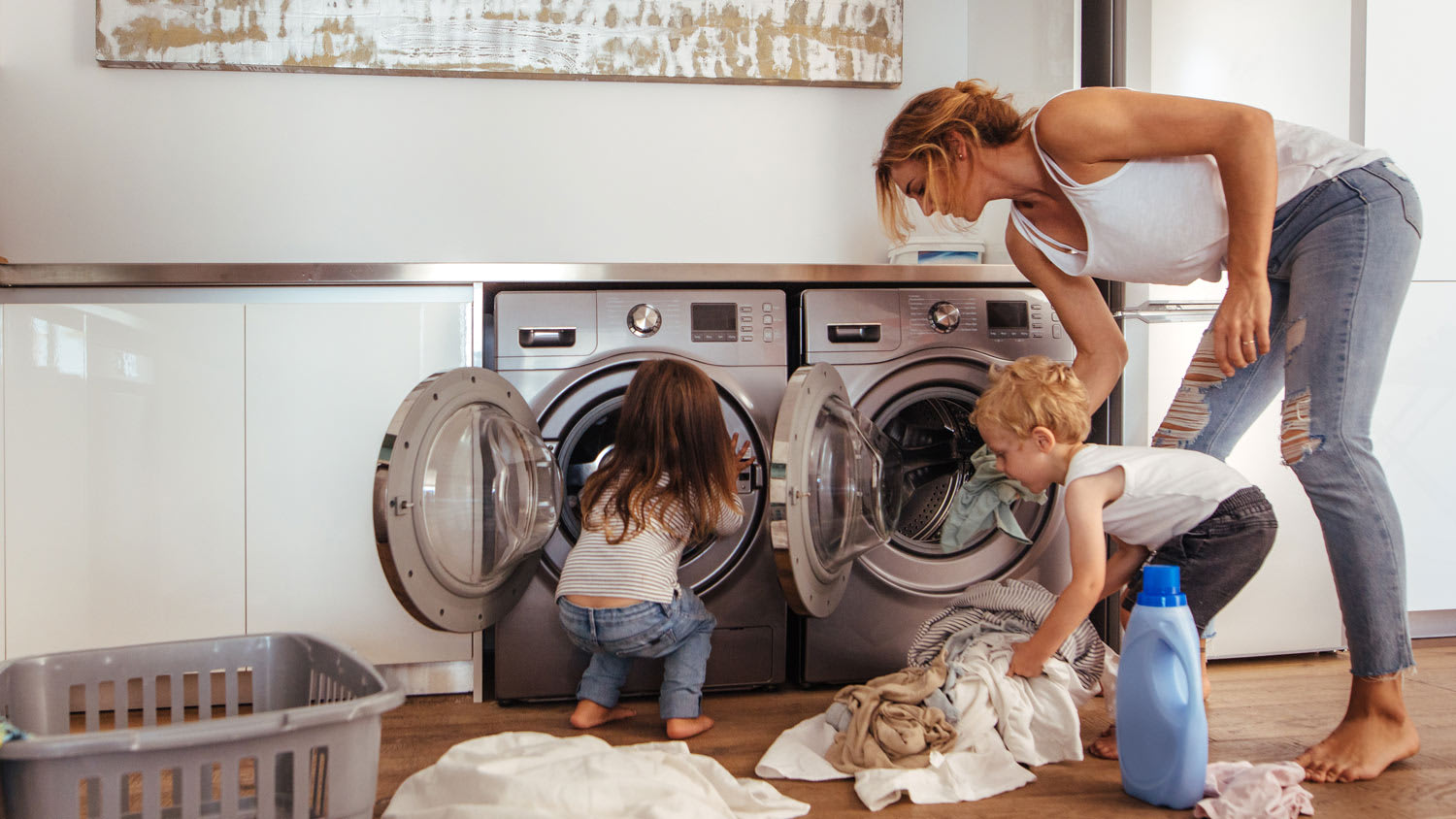A mom with her children loading the washing machine with clothes