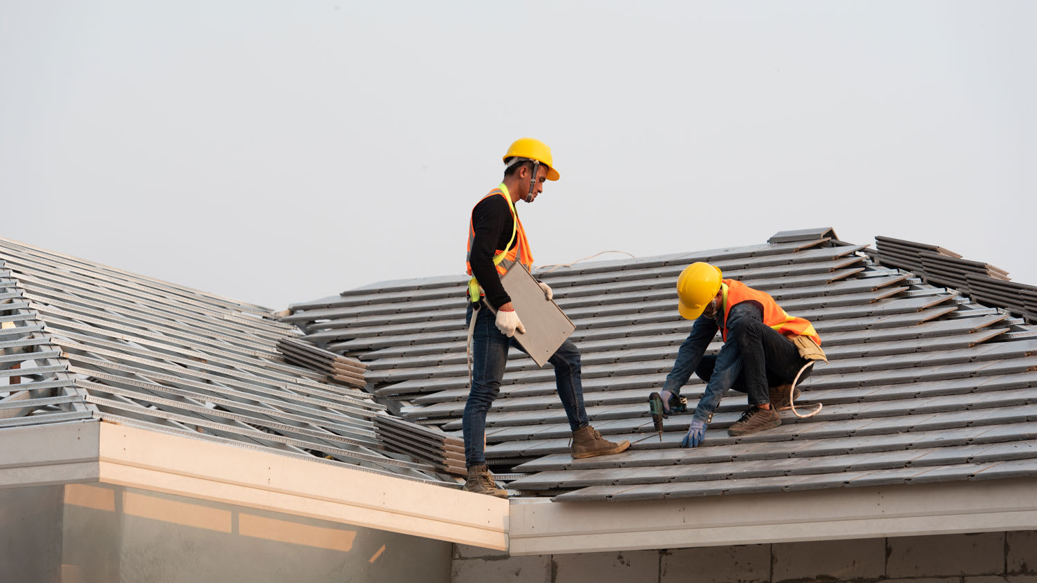 A group of roofers installing ceramic tiles on a roof