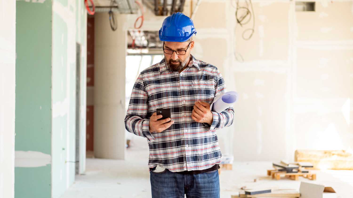 A contractor checking his phone while being on construction site
