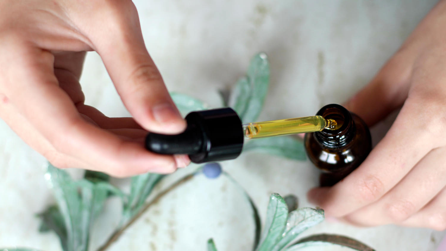 A woman holding an essential oil pipette