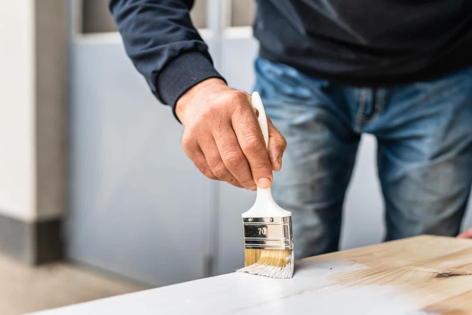 Close up of a man painting a wooden board
