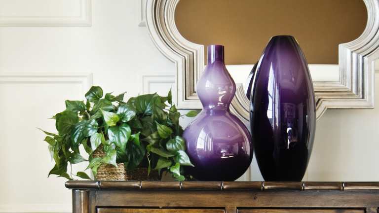 Bedroom dresser with purple vases and plants