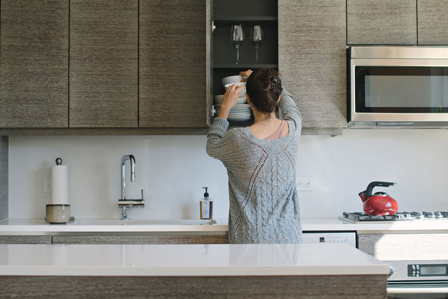 woman putting dishes away in cabinets