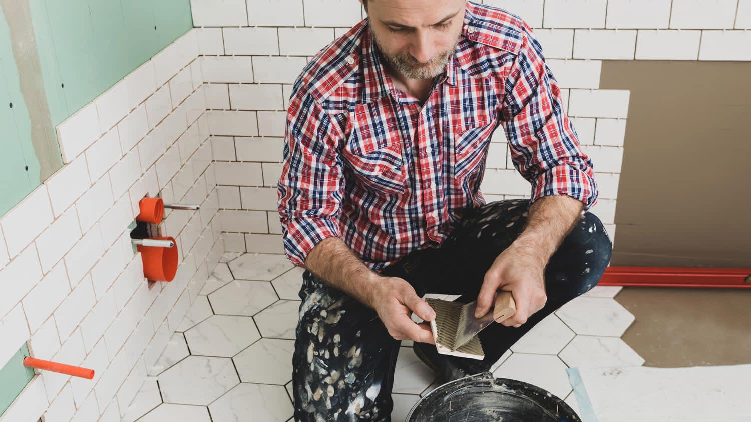 Tiler lays ceramic tiles on bathroom walls and floors