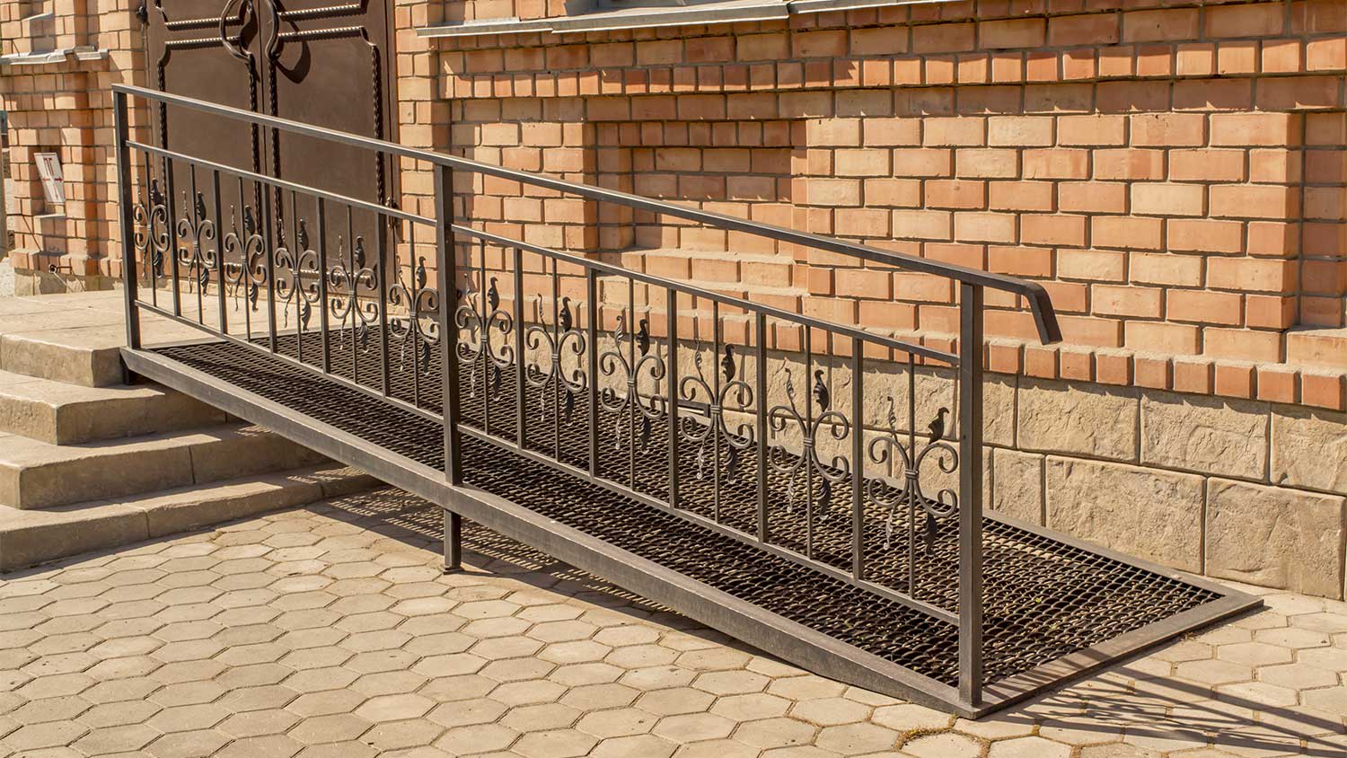 Metal wheel chair ramp outside of a brick building