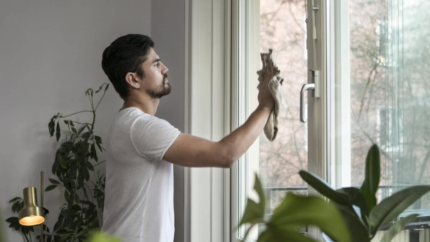 Man cleaning glass window in living room