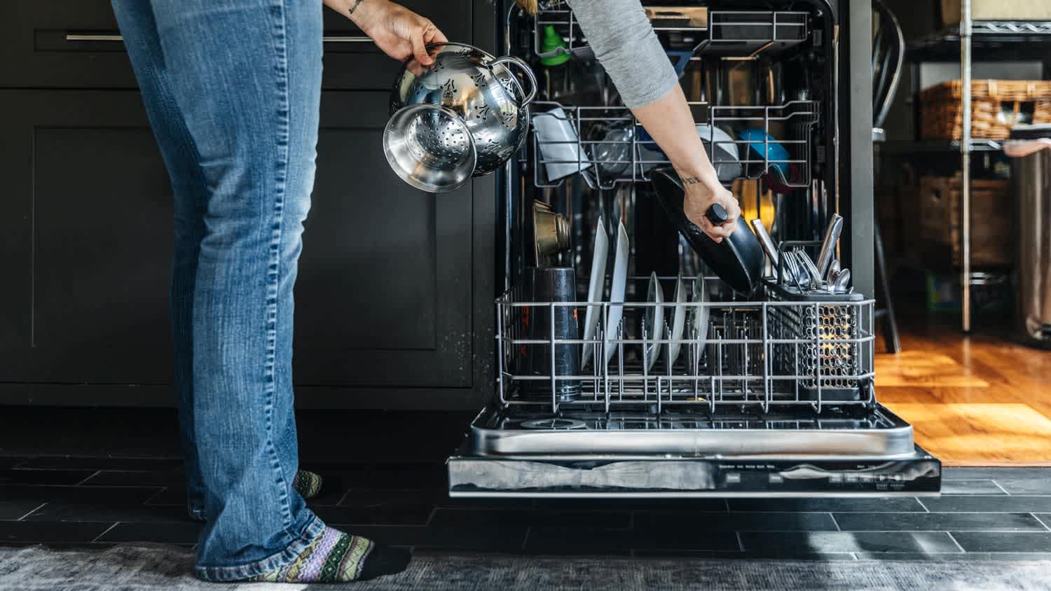 A woman arranging utensils in dishwasher