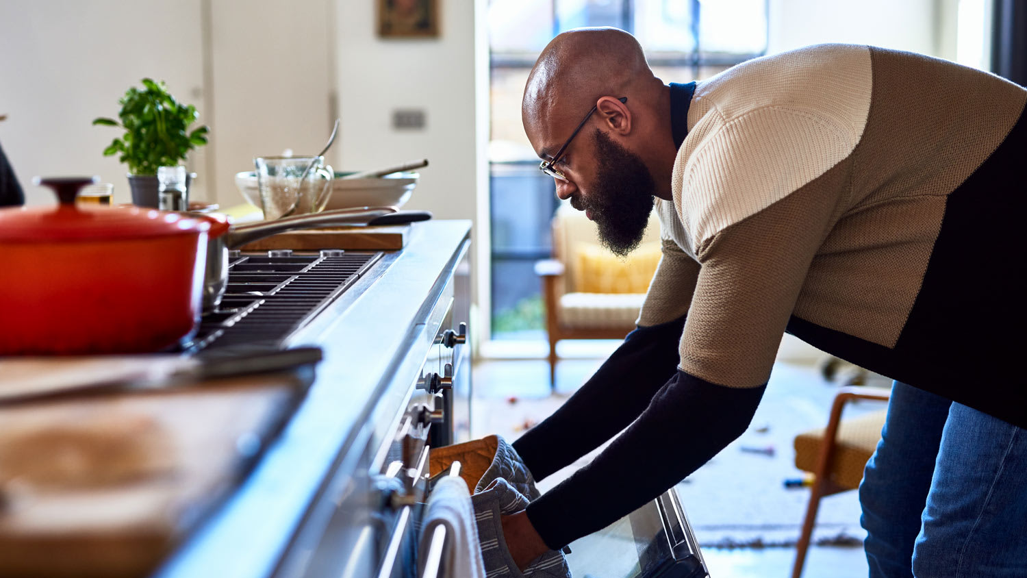 A man is cooking dinner by placing a pan into the oven