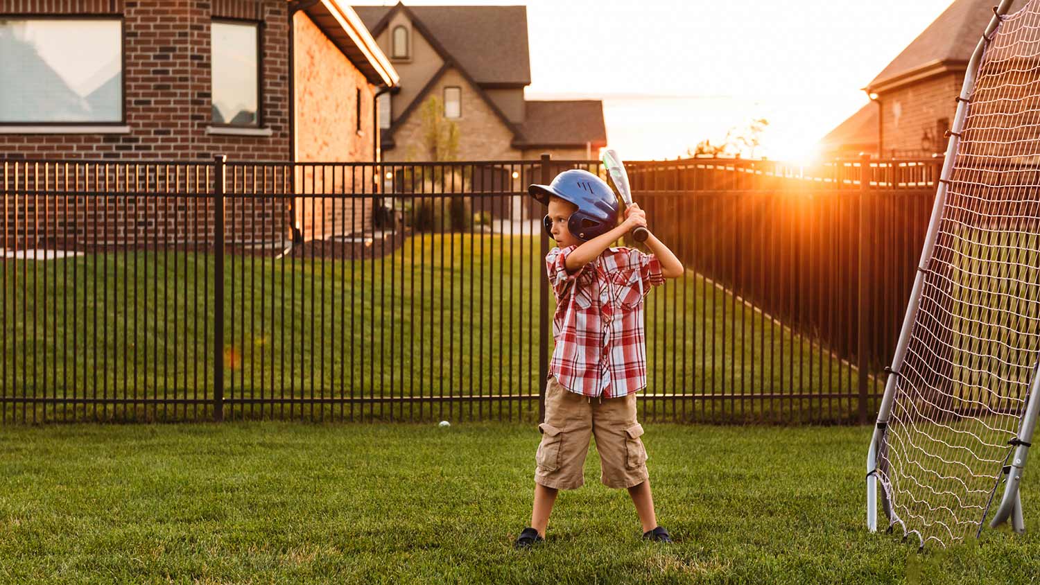 Kid playing baseball outside house