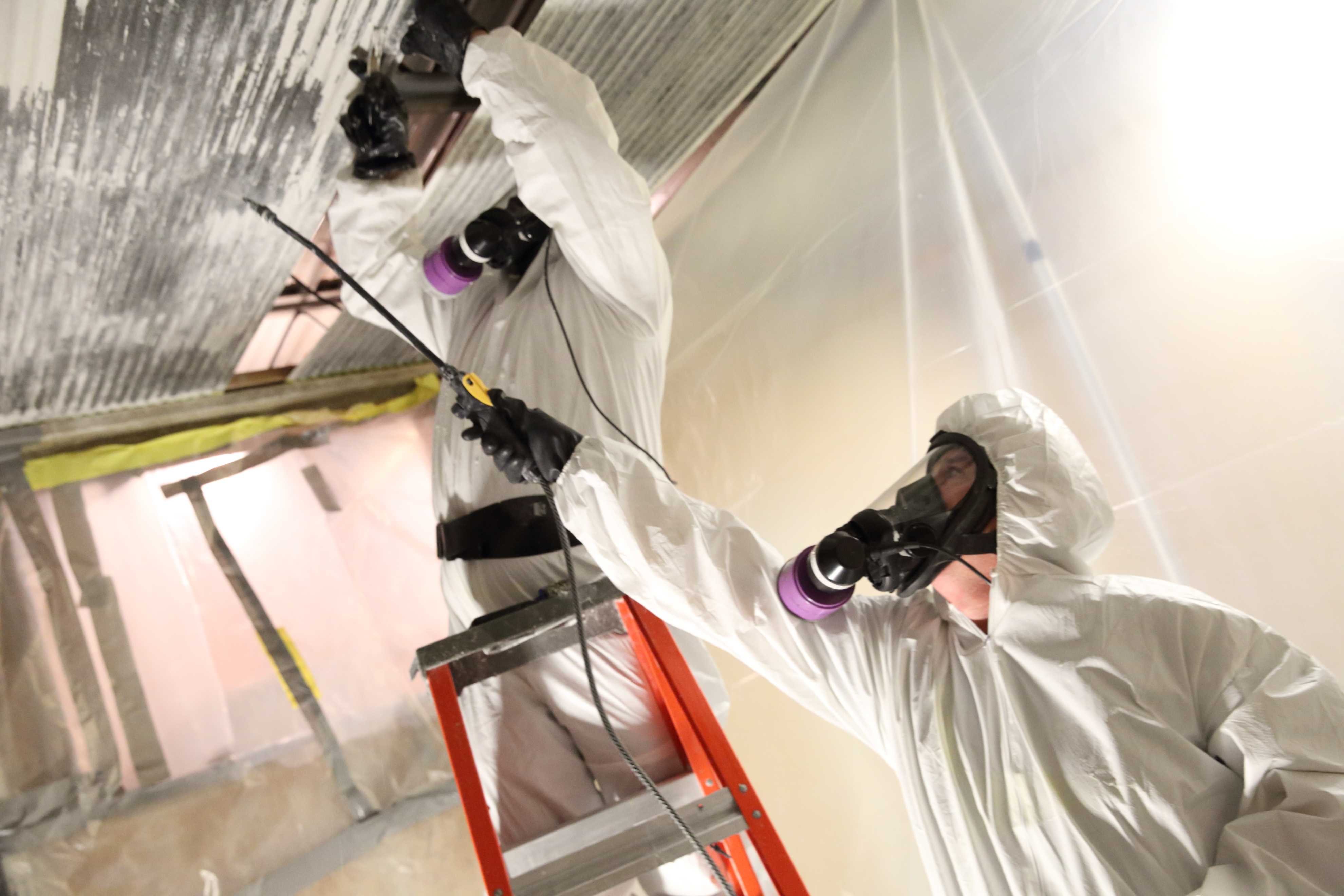 men wearing white suits, masks, removing asbestos