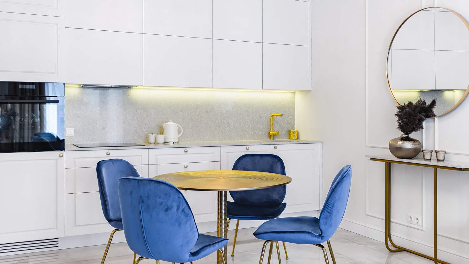 A minimal kitchen with an eating area with four velvet chairs