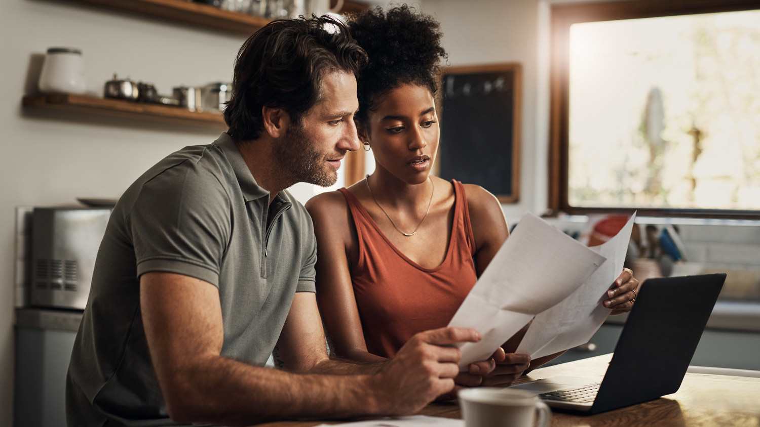 A couple looking at their laptop and some papers