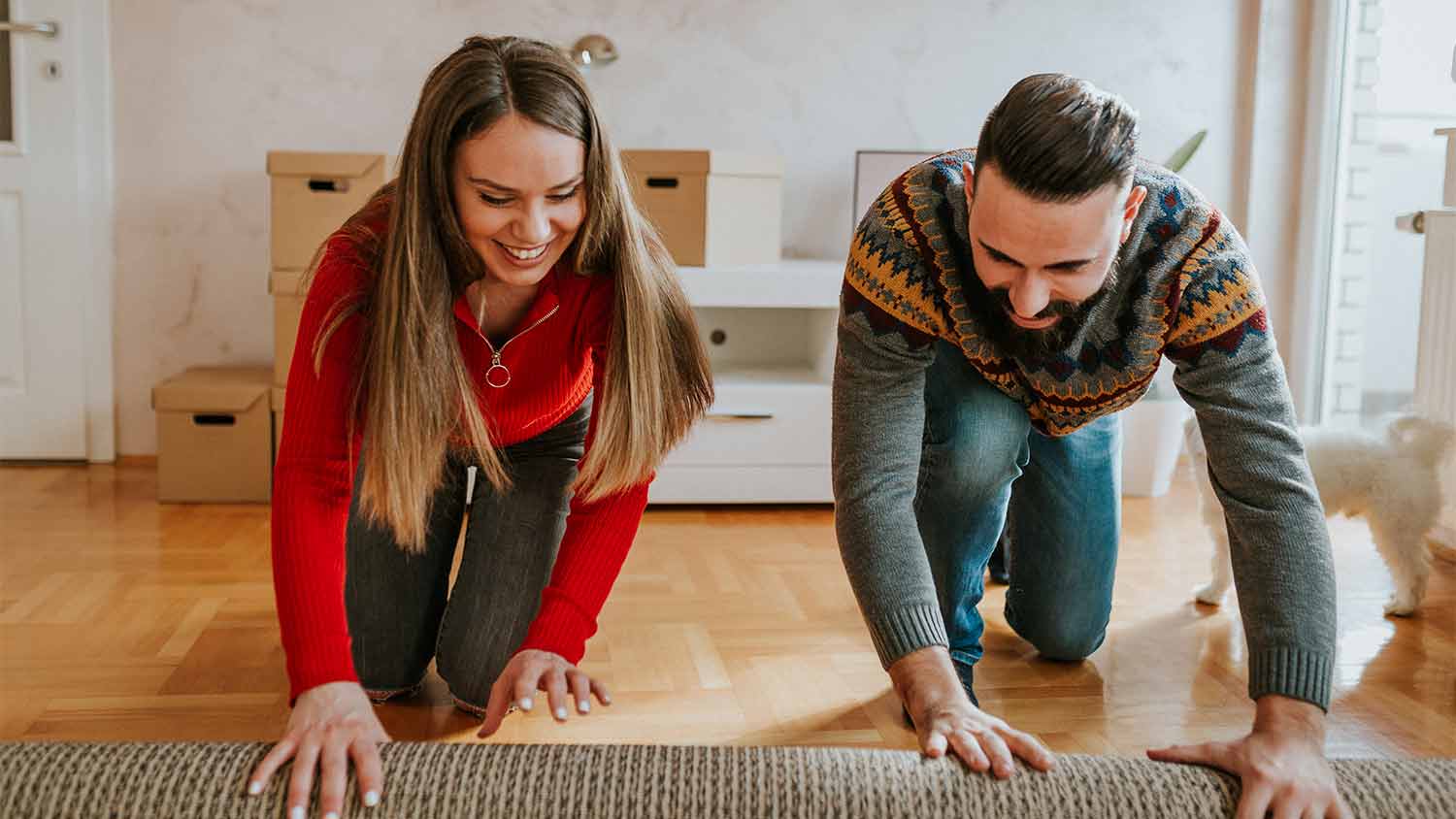 couple rolling up rug in apartment